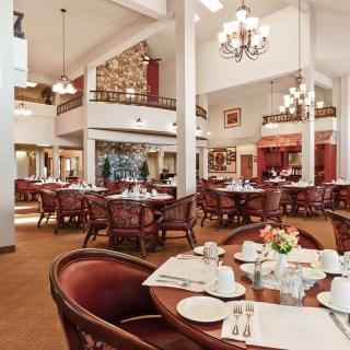 A cozy restaurant dining room with elegantly set tables and chandeliers.