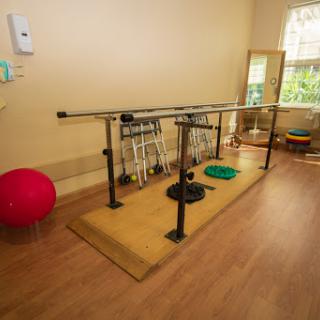 A well-equipped rehabilitation space featuring a balance bar and various exercise tools.