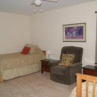 A cozy bedroom with a bed, recliner, nightstand, and wall artwork.