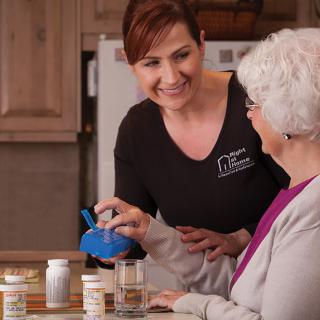 A caregiver assisting an elderly woman with her medication at home.