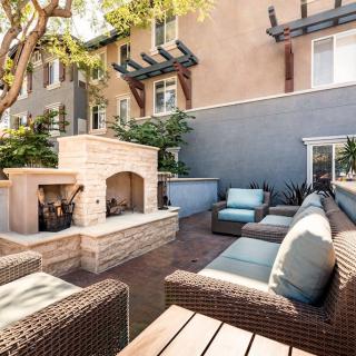 A cozy outdoor patio with comfortable wicker furniture and a built-in brick fireplace.