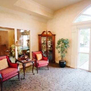 A cozy living room with elegant chairs, a decorative cabinet, and a large window providing natural light.
