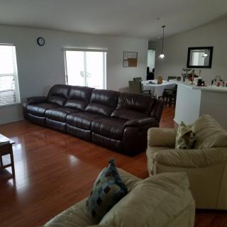 A spacious living room with a large leather sofa, comfortable chairs, and hardwood flooring.