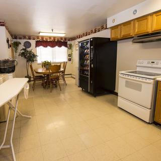 A cozy kitchen and dining area featuring a stove, refrigerator, and a wooden dining set.