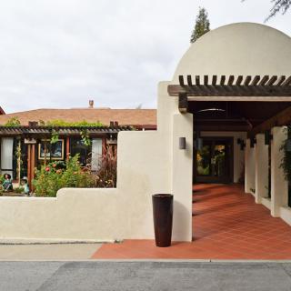 A view of an entrance with a covered walkway and garden.