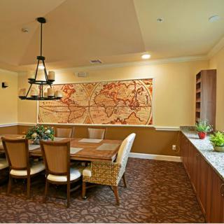 A cozy dining room featuring a large wooden table, elegant chairs, a world map wall art, and a chandelier.