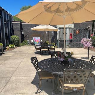 A sunny outdoor patio area featuring tables with umbrellas and blooming flowers.