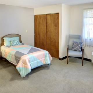 A minimalist bedroom with a single bed, chair, and closet.