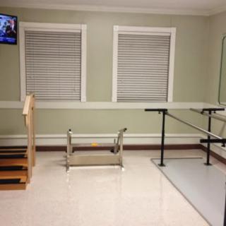 A rehabilitation room equipped with parallel bars and therapy stairs for physical therapy exercises.