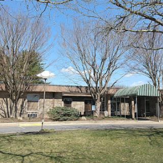 A view of a building surrounded by trees and grass under a clear blue sky.