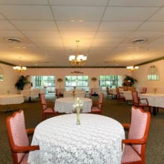 A spacious dining room with elegantly set tables, featuring floral arrangements and comfortable seating.