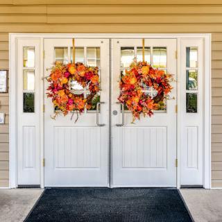 A pair of white double doors decorated with vibrant autumn wreaths.