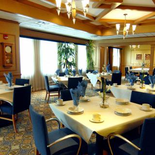 An elegant dining room with neatly arranged tables and chairs, set for a formal meal.