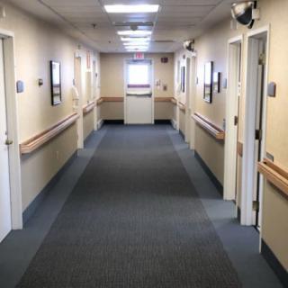 A well-lit hospital corridor with doors on either side.