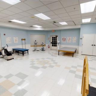 A spacious physical therapy room with various rehabilitation equipment and exercise tables.
