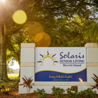 Welcoming sign for Solaris Senior Living, set against a lush outdoor backdrop.