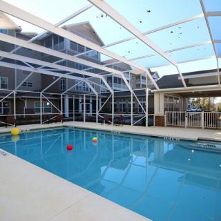 A spacious indoor swimming pool enclosed by a clear, structured roof, situated in a residential setting.