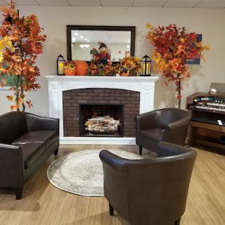 A cozy living room setup adorned with autumn decorations, featuring a warm fireplace and comfortable seating.