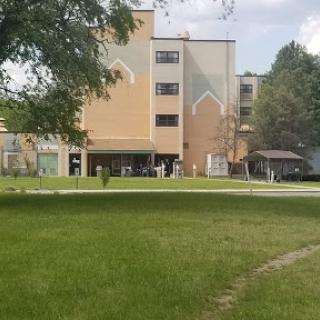 A view of a modern building surrounded by green grass and trees.