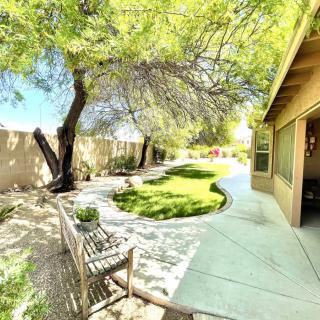 A sunny backyard with a lush garden, trees, and a cozy seating area.