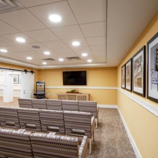 A neatly arranged conference room with rows of chairs facing a large television and projector screen.