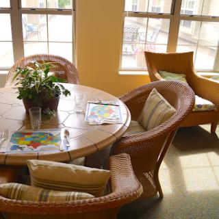 A cozy dining area with a round table, comfortable chairs, and a decorative plant, bathed in natural light.