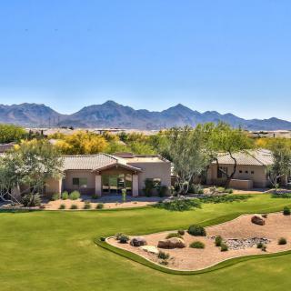 A beautiful house surrounded by a lush landscape with mountains in the background.