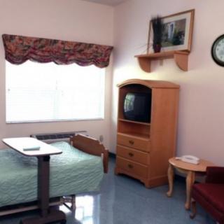 A hospital room with a single bed, television, and basic furniture.