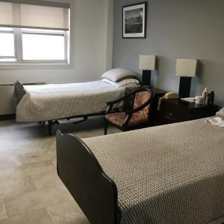 A minimalist bedroom with two twin beds, a window, and simple furnishings.