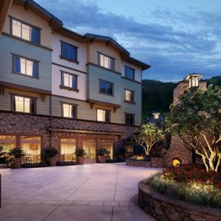 An elegant hotel building at dusk with illuminated windows and a landscaped courtyard.