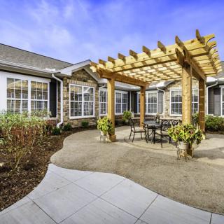 A beautifully landscaped patio featuring a wooden pergola and outdoor seating.