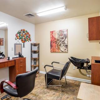 A cozy hair salon featuring chairs, mirrors, and colorful artwork on the walls.