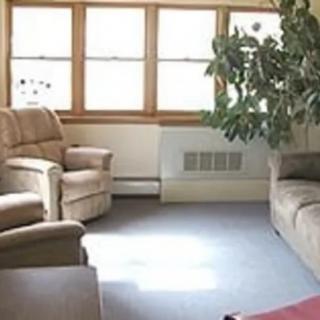 A cozy living room with comfortable chairs, a sofa, and large windows that let in natural light.