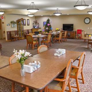 A well-lit dining area with neatly arranged tables and chairs, decorated with flowers.