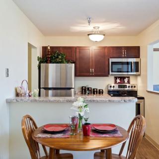 A cozy kitchen with a small dining area featuring modern appliances and a wooden table set.
