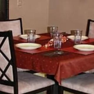 A dining table set for four with a red tablecloth and neatly arranged dinnerware.