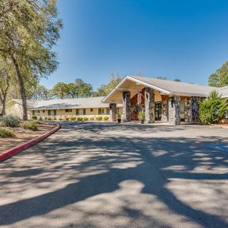 A daytime view of a motel's exterior with a driveway and surrounding trees.