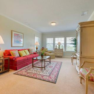 A bright and classic living room featuring a red sofa, coffee table, and armchair.