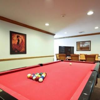 A cozy game room featuring a red-felt pool table and framed artwork on the walls.