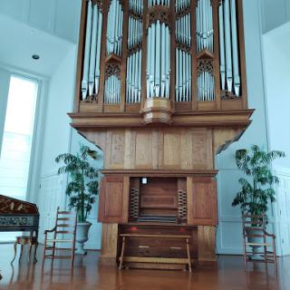 A beautifully crafted wooden organ situated in a well-lit interior space.