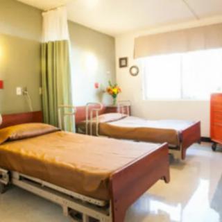 A well-lit hospital room with two beds and medical equipment.