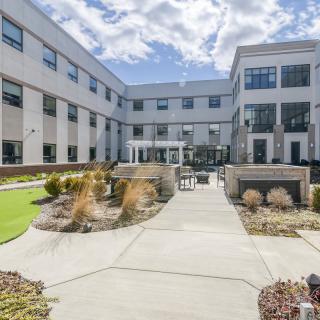 A modern building with a landscaped courtyard featuring pathways and outdoor seating.