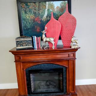 A stylish living room display featuring a decorative fireplace, vibrant vases, and an artistic touch.