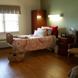 A cozy bedroom with a single bed, featuring wooden flooring and ample natural light.