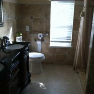 A well-lit bathroom with a sink and toilet, featuring tile walls and flooring.