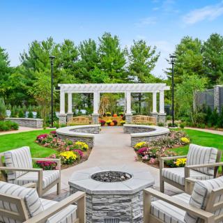 A beautifully landscaped outdoor patio with a fire pit and seating area surrounded by greenery.