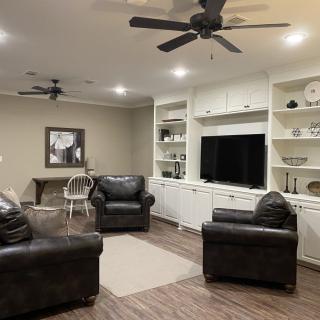 A cozy living room with leather chairs, built-in shelves, and a large television.