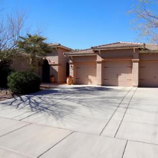A suburban house with a three-car garage and spacious driveway on a sunny day.