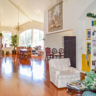 A bright and spacious living room with wooden flooring, featuring a dining area, comfortable seating, and tasteful decor.
