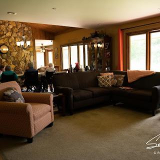 A cozy living room with a brown sofa, armchair, and adjoining dining area.